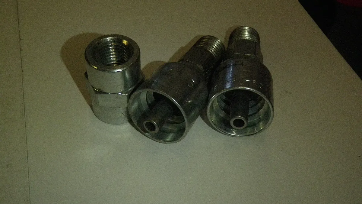 Assorted hydraulic hose fittings and coupling bodies on a bench